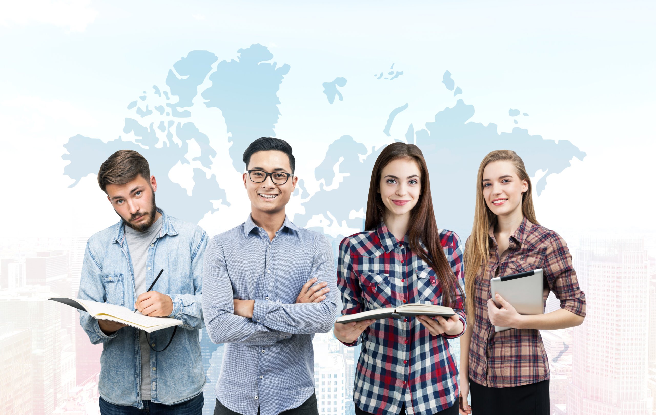 Portrait of a young business team standing with books and a tablet computer near a white wall with a world map drawn on it. Elements of this image furnished by NASA